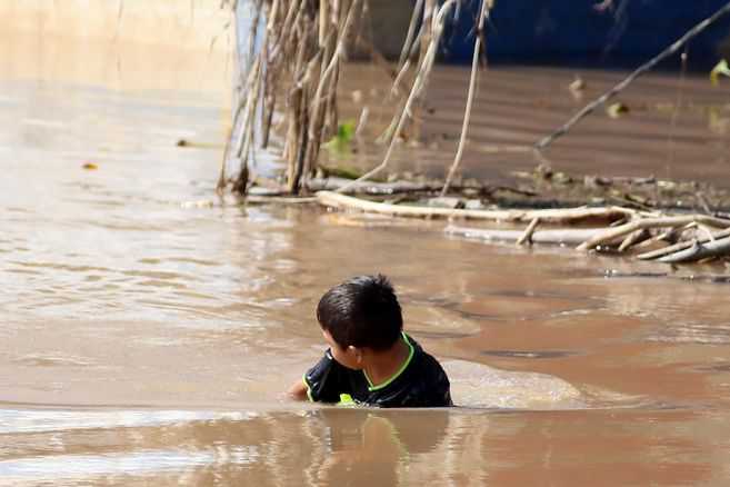 Niños hondureños víctimas de huracanes se bañan en aguas estancadas